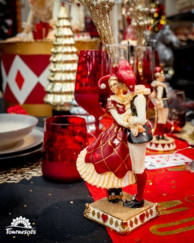 Décoration de table de Noël avec figurine Renaissance et verres rouges.